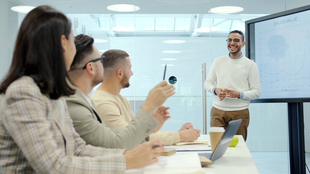 Cheerful Middle Eastern man speaking to group of people in conference room using digital screen with presentation discussing business questions.