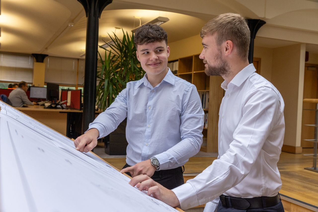 Two young professionals discussing plans in a modern, well-lit office setting.